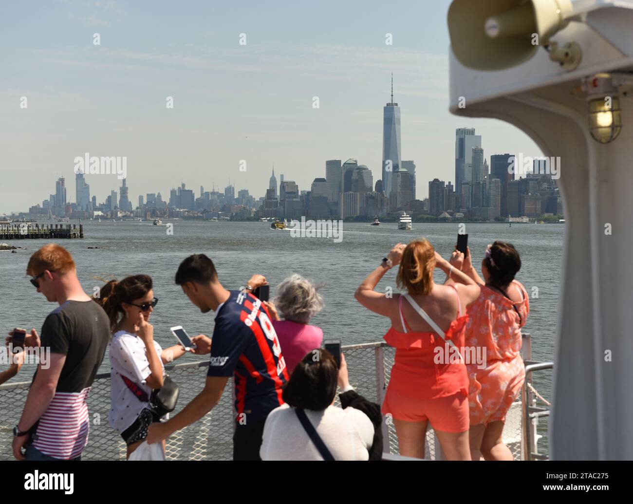 New York, USA - June 09, 2018: Passengers of the Statue of Liberty Ferry and  buildings of financial district in lower Manhattan at the background. Stock Photo