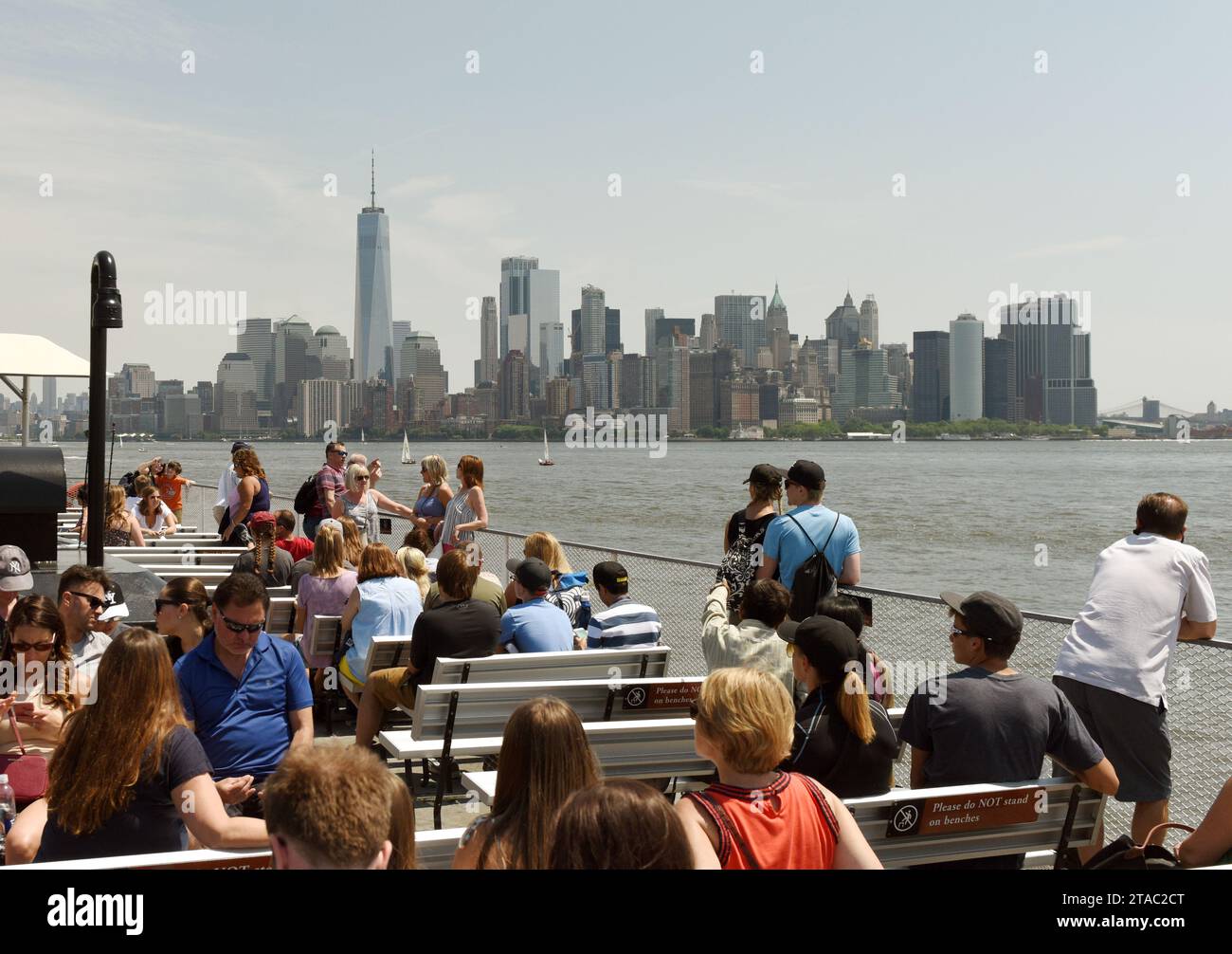 New York, USA - June 09, 2018: Passengers of the Statue of Liberty Ferry and  buildings of financial district in lower Manhattan at the background. Stock Photo