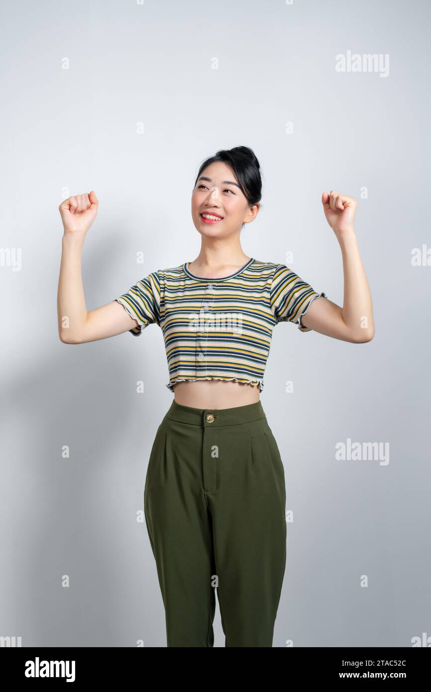 Beautiful Asian woman raises arms and fists clenched with shows strong powerful, Stock Photo