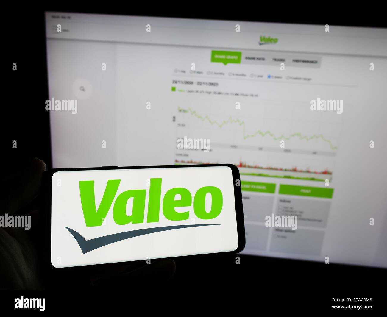 Person holding smartphone with logo of French automotive supply company Valeo S.A. in front of website. Focus on phone display. Stock Photo