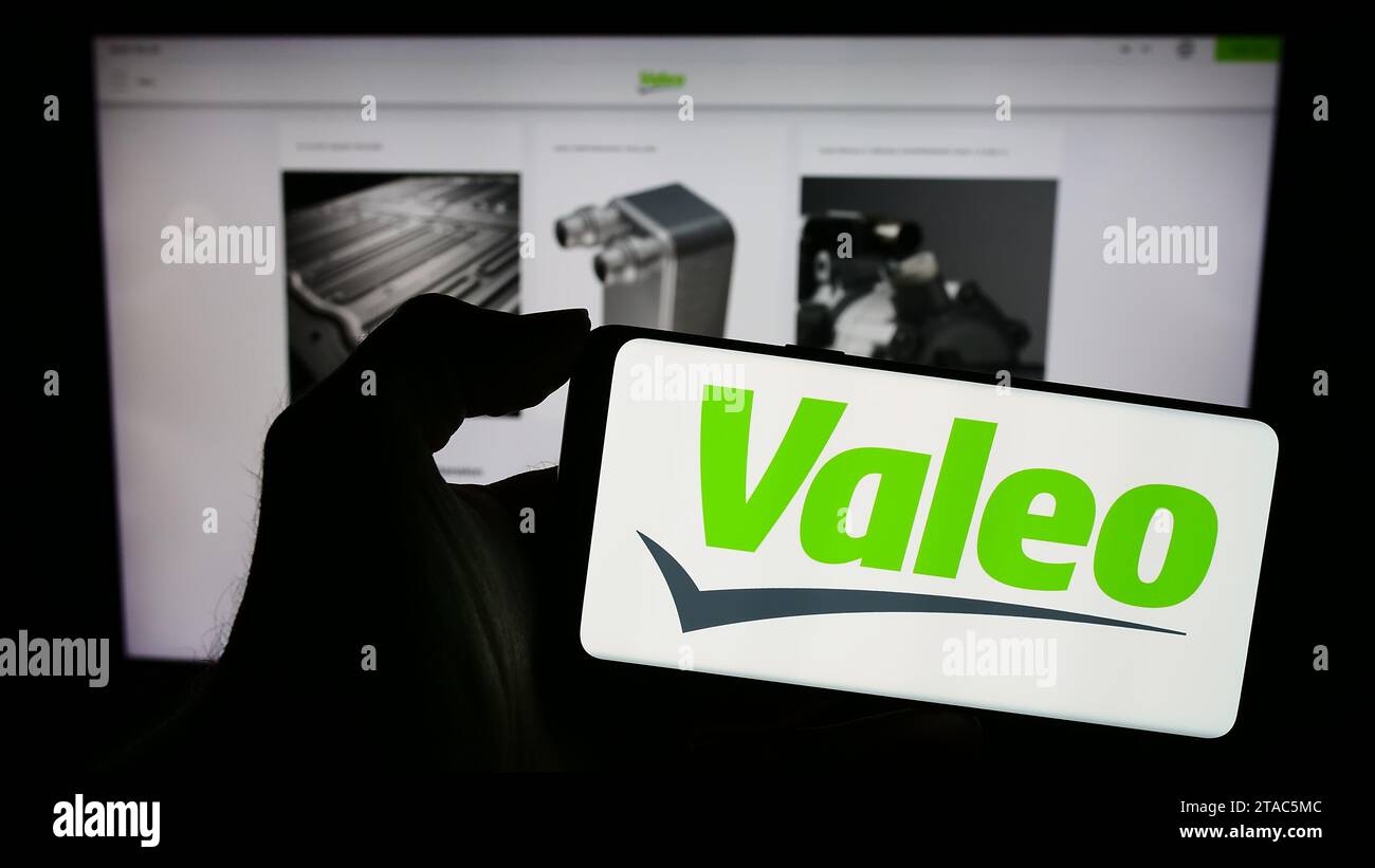 Person holding mobile phone with logo of French automotive supply