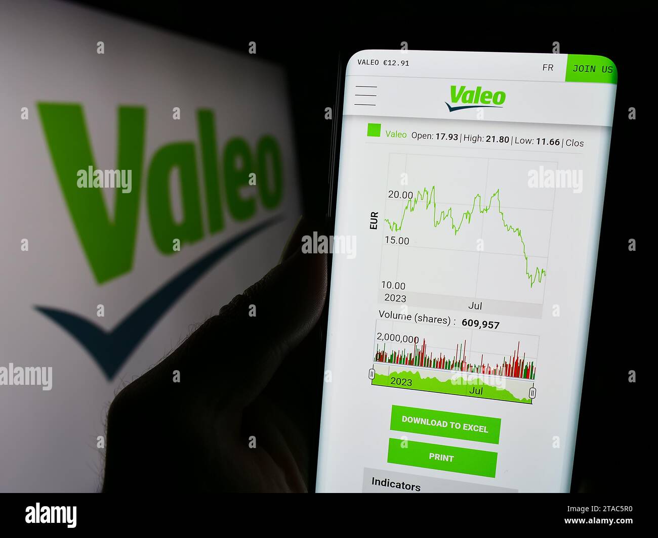 Person holding cellphone with website of French automotive supply company Valeo S.A. in front of business logo. Focus on center of phone display. Stock Photo