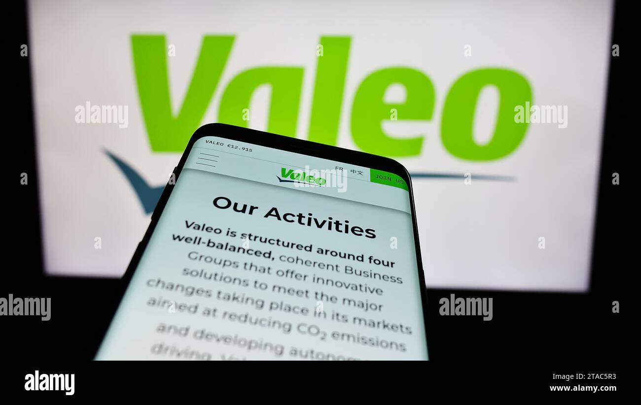 Mobile phone with webpage of French automotive supply company Valeo S.A. in front of business logo. Focus on top-left of phone display. Stock Photo