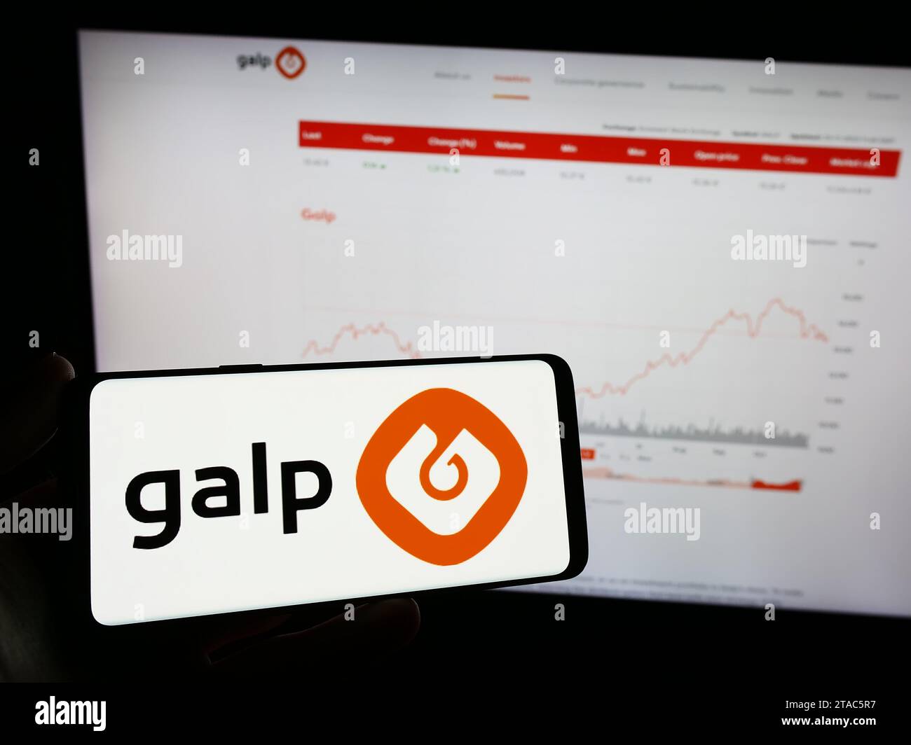 Person holding mobile phone with logo of Portuguese energy company Galp Energia SGPS S.A. in front of business web page. Focus on phone display. Stock Photo