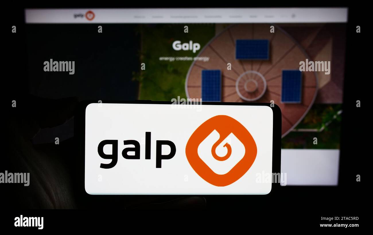 Person holding smartphone with logo of Portuguese energy company Galp Energia SGPS S.A. in front of website. Focus on phone display. Stock Photo