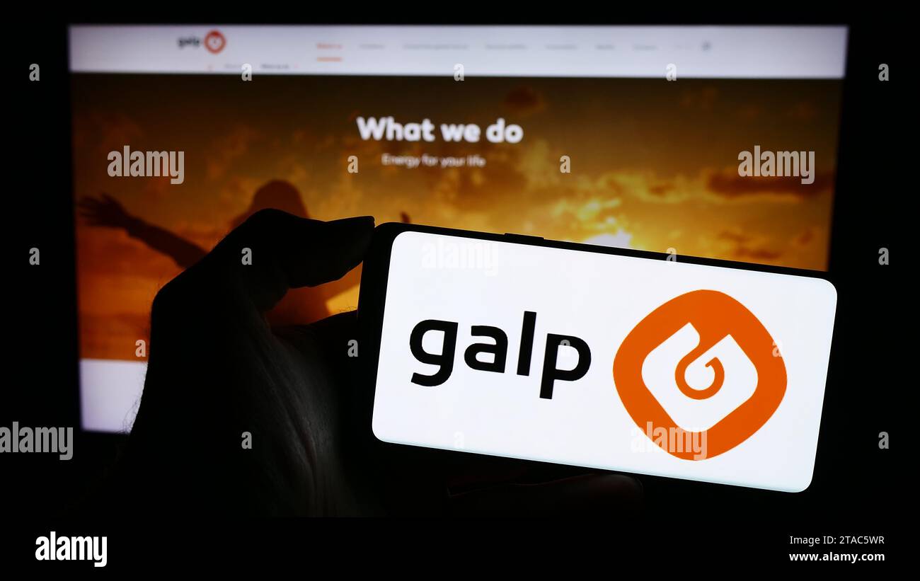 Person holding cellphone with logo of Portuguese energy company Galp Energia SGPS S.A. in front of business webpage. Focus on phone display. Stock Photo