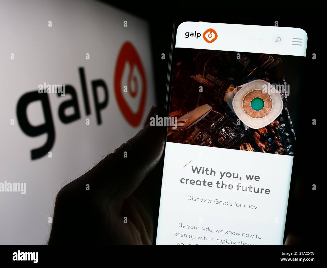 Person holding cellphone with webpage of Portuguese energy company Galp Energia SGPS S.A. in front of logo. Focus on center of phone display. Stock Photo