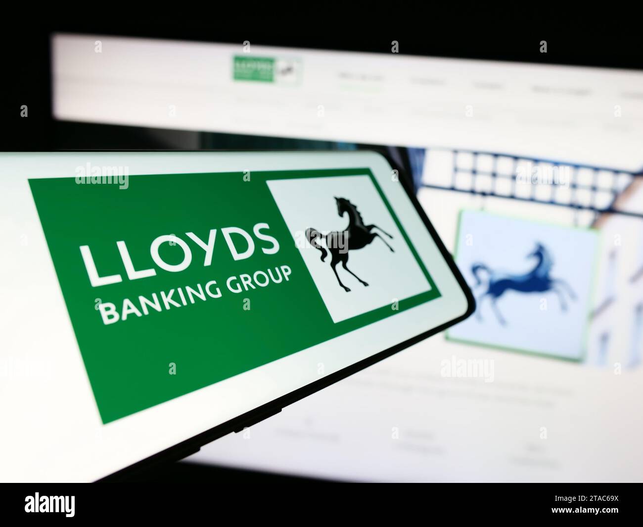 Cellphone with logo of British financial company Lloyds Banking Group plc in front of business website. Focus on center-left of phone display. Stock Photo