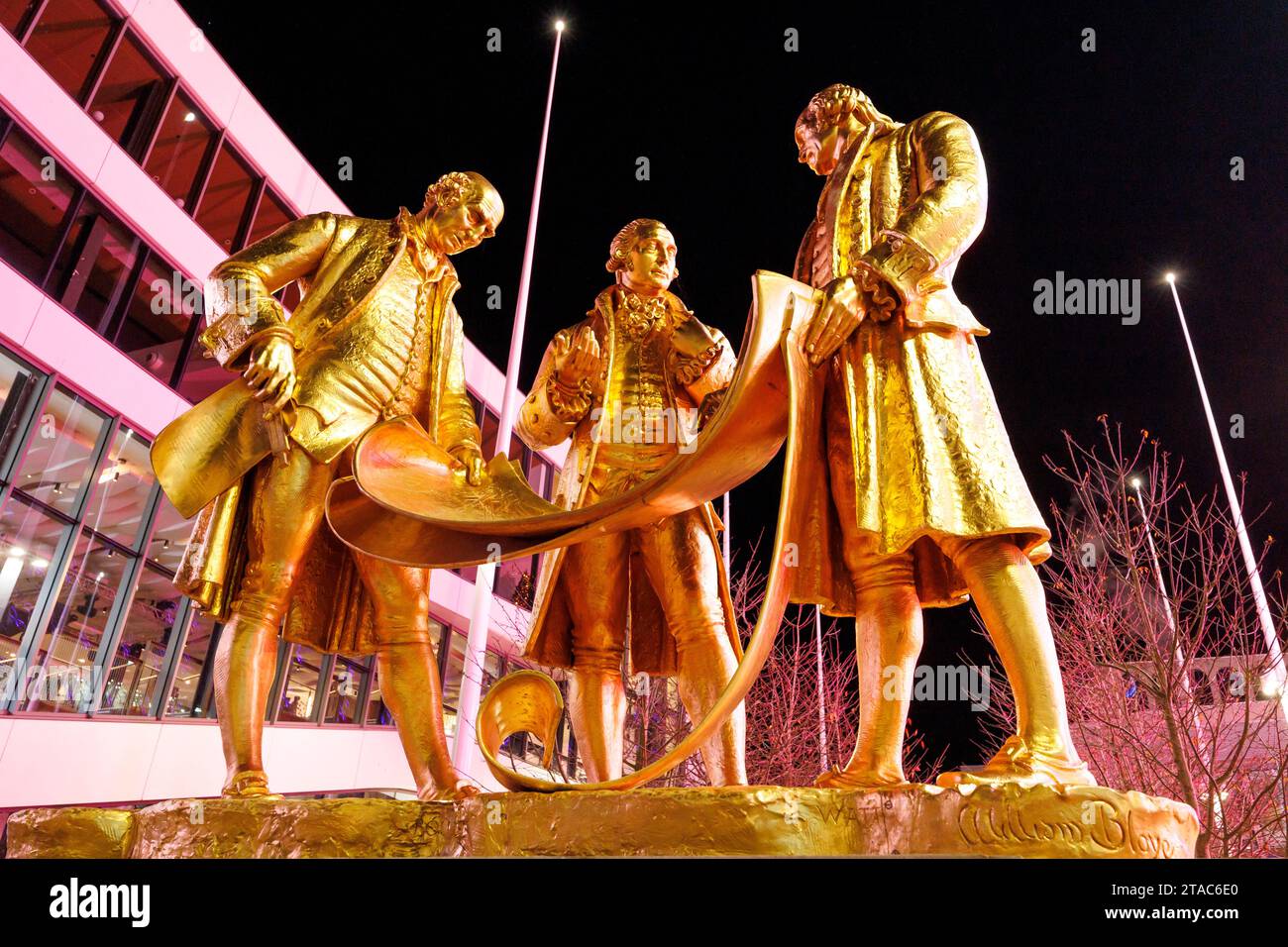 Statue of Matthew Boulton, James Watt, and William Murdoch by William Boyle situated on Broad Street, Birmingham. This gilded bronze statue, known as the ‘Golden Boys’ (and also the ‘Carpet Salesmen’!) honours Matthew Boulton, James Watt and William Murdoch. They are shown studying steam engine plans.  Together these three revolutionised the steam engine – the technology that would literally drive the industrial revolution. Stock Photo