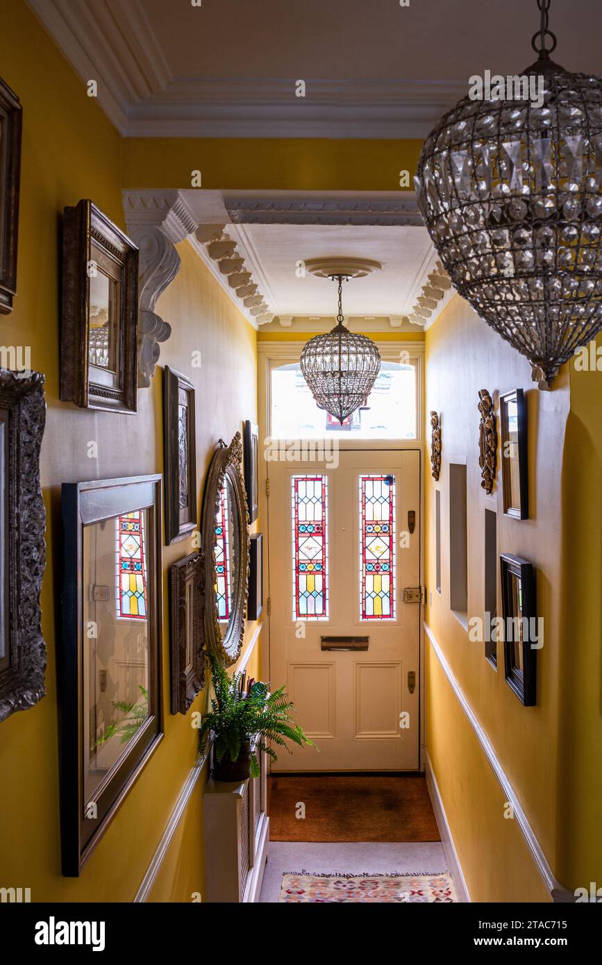Glass pendant shades with stained glass door panels in yellow hallway of late 19th century West London home. Stock Photo