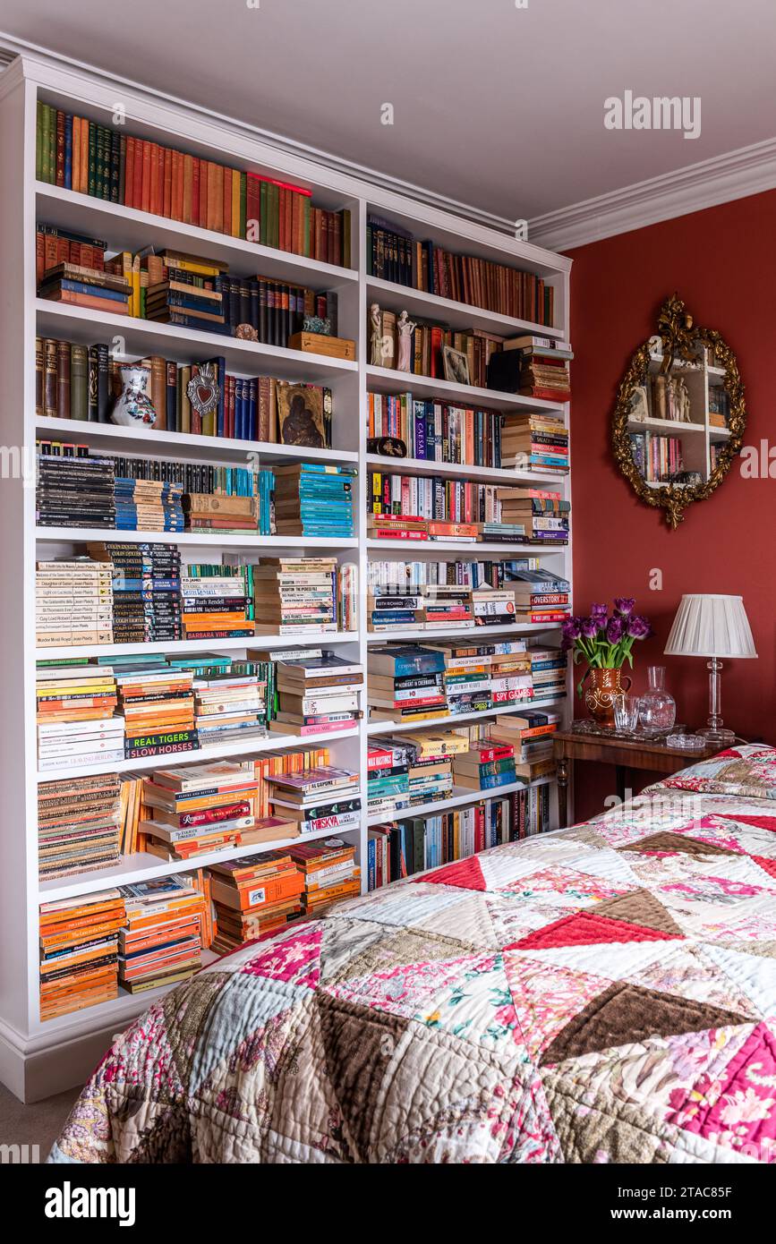 Paperback book collection in Egyptian red guest room of late 19th century West London home. Stock Photo