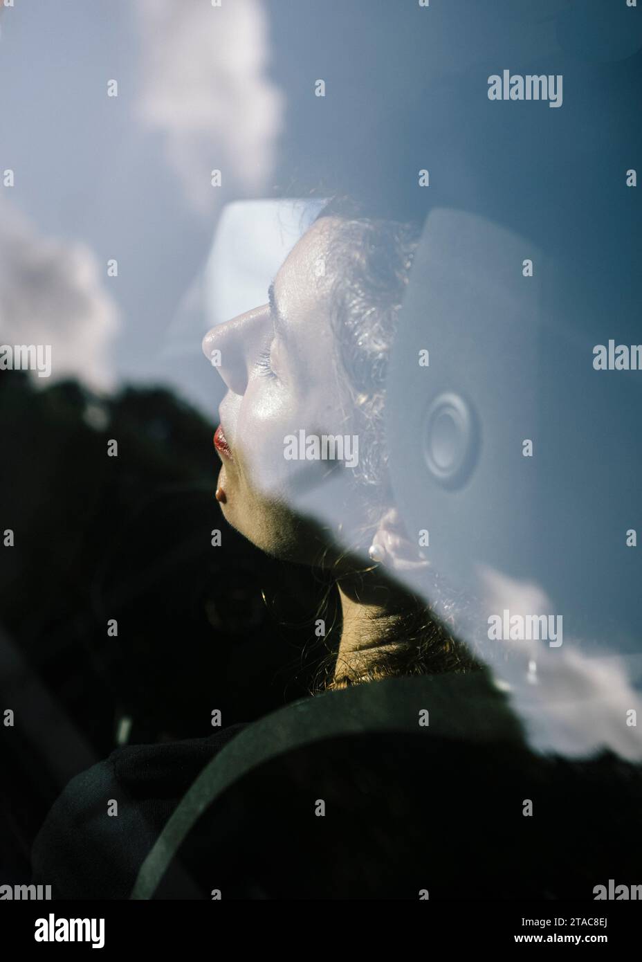 40-year-old woman sitting in the car. Close-up of her face and the reflection of the sky. Stock Photo