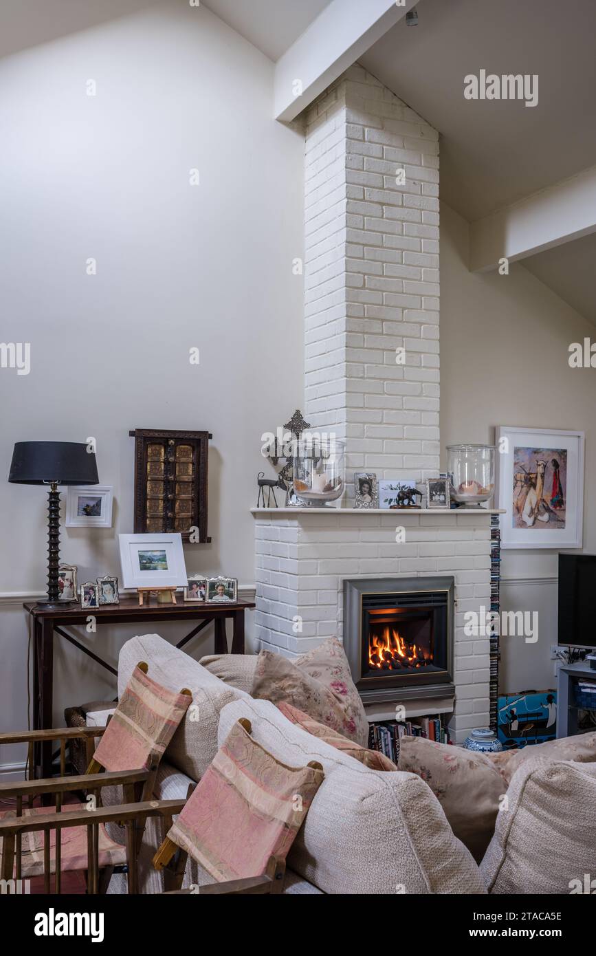 Painted brick fireplace with 'real flame' gas fire in colonial style single-storey Truro home, Cornwall, UK. Stock Photo