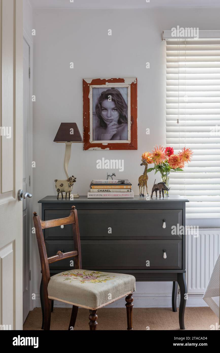 Grey chest of drawers with portrait and chair in single-storey home in Truro, Cornwall, UK. Stock Photo