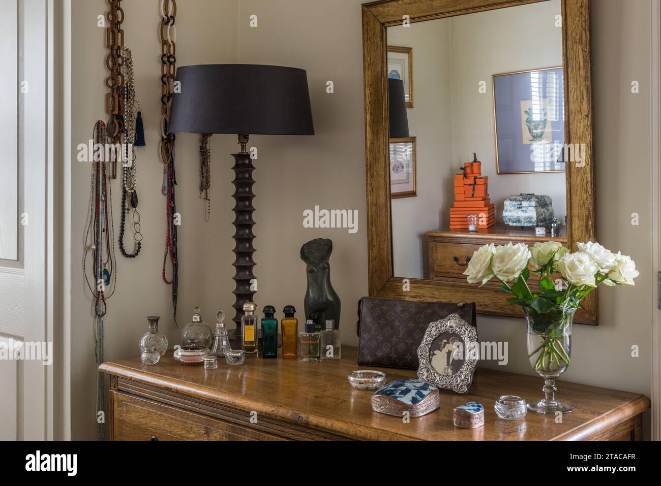 African necklaces and perfume on dressing table in colonial style single-storey home. Truro, Cornwall, UK. Stock Photo