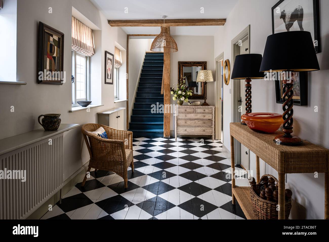 Black and white painted floor with 'Hague Blue' staircase in entrance hall of 1930s Arts and Crafts style home. Hove, East Sussex, UK. Stock Photo