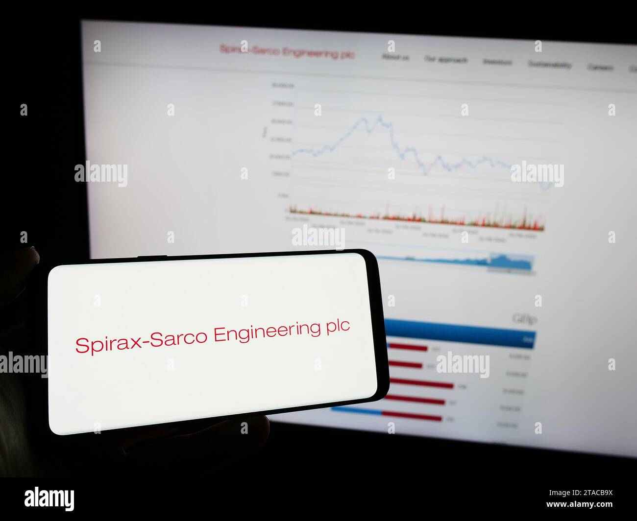 Person holding mobile phone with logo of British company Spirax-Sarco Engineering plc in front of business web page. Focus on phone display. Stock Photo