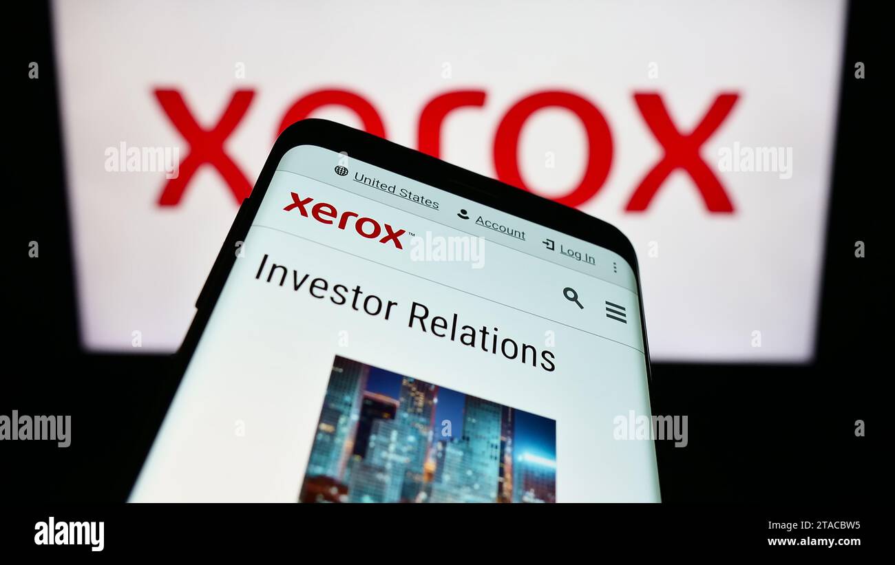 Smartphone with website of US printer company Xerox Holdings Corporation in front of business logo. Focus on top-left of phone display. Stock Photo