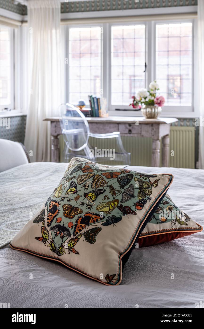 Liberty butterfly print cushions with Louis Ghost chair at Indian table in window of 1930s Arts and Crafts style home. Hove, East Sussex, UK. Stock Photo