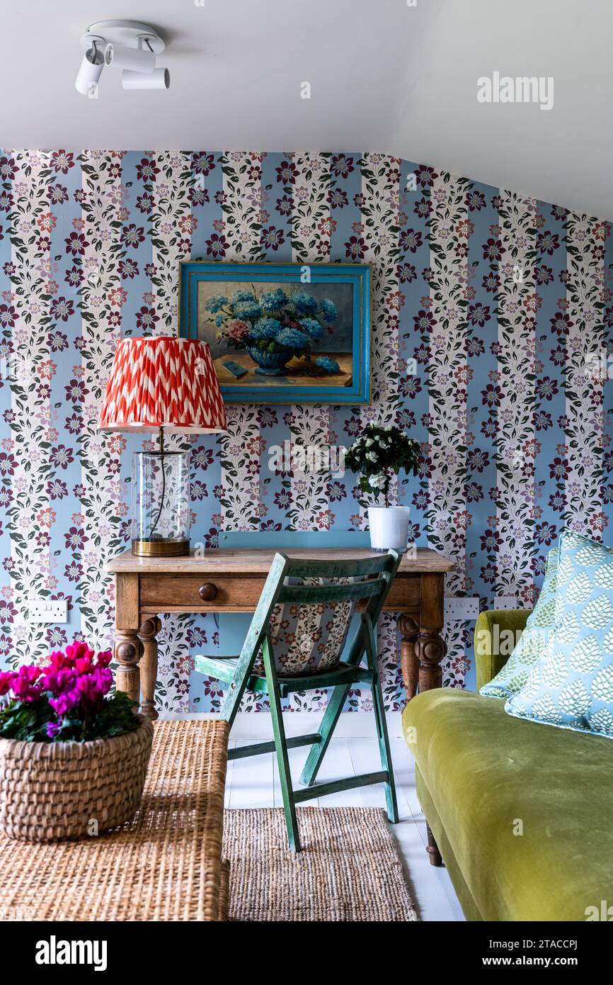 Floral striped wallpaper by Eloise Home with botanic artwork and cyclamen in 1930s Arts and Crafts style garden room. Hove, East Sussex, UK Stock Photo