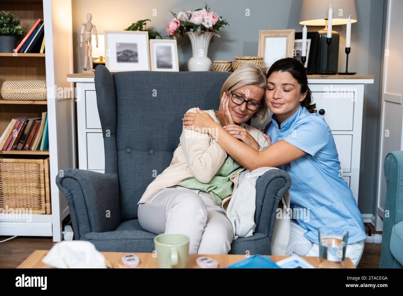 Caring young woman nurse help old granny during homecare medical visit, female caretaker doctor talk with elder lady give empathy support encourage pa Stock Photo