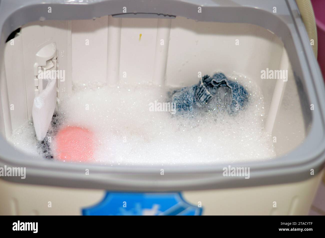 manual top load washing machine, laundry clothes washer, a home appliance used to wash laundry, user adds laundry detergent, which is sold in liquid, Stock Photo