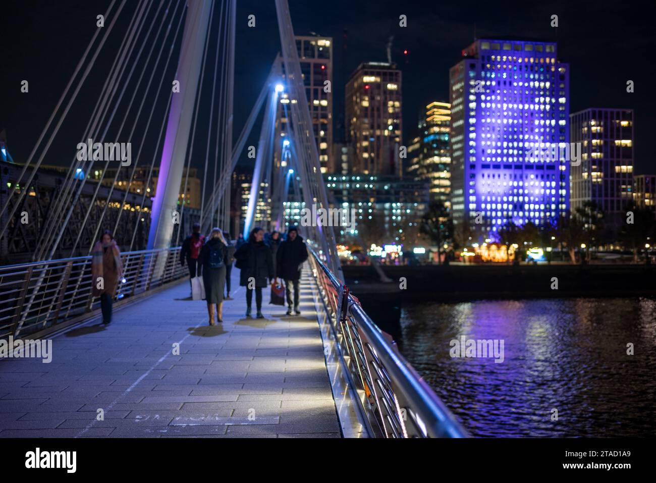 People crossing on Golden Jubilee Bridge over The River Thames at night, London Stock Photo