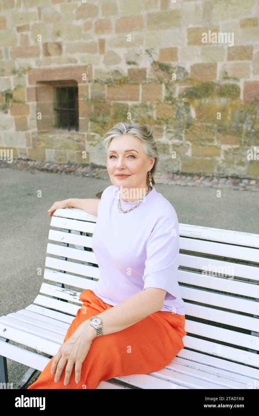 Outdoor portrait of mature happy woamn relaxing on a bench Stock Photo ...