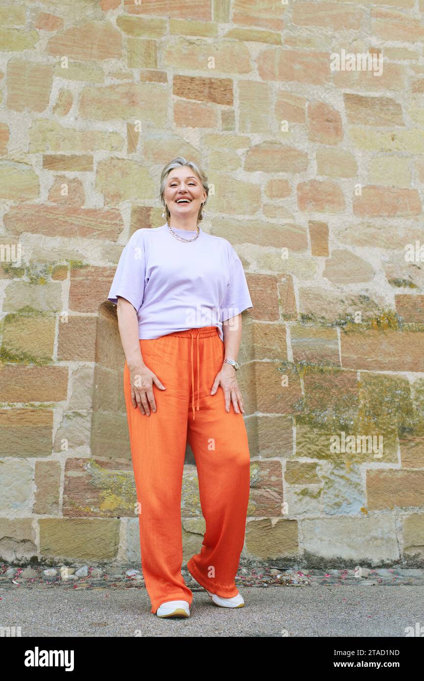 https://c8.alamy.com/comp/2TAD1ND/outdoor-fashion-portrait-of-stylish-mature-woman-with-grey-hair-wearing-violet-top-and-orange-pants-2TAD1ND.jpg