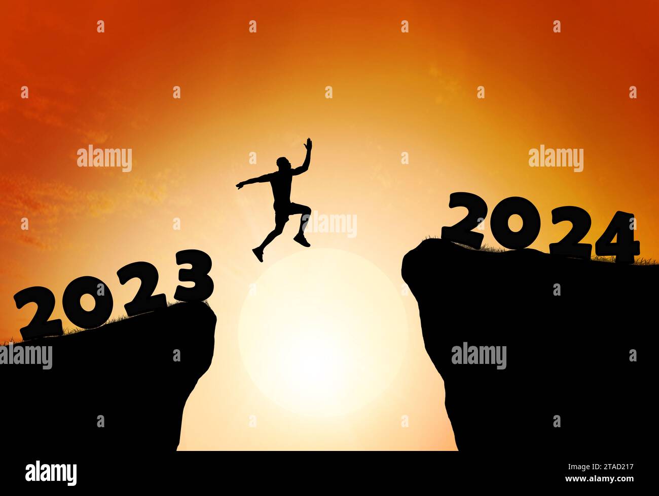 Greetings and have a great Christmas and new year in 2024.silhouette of a man leaping from a cliff in 2023 to one in 2024 under a cloudy and sunny sky Stock Photo