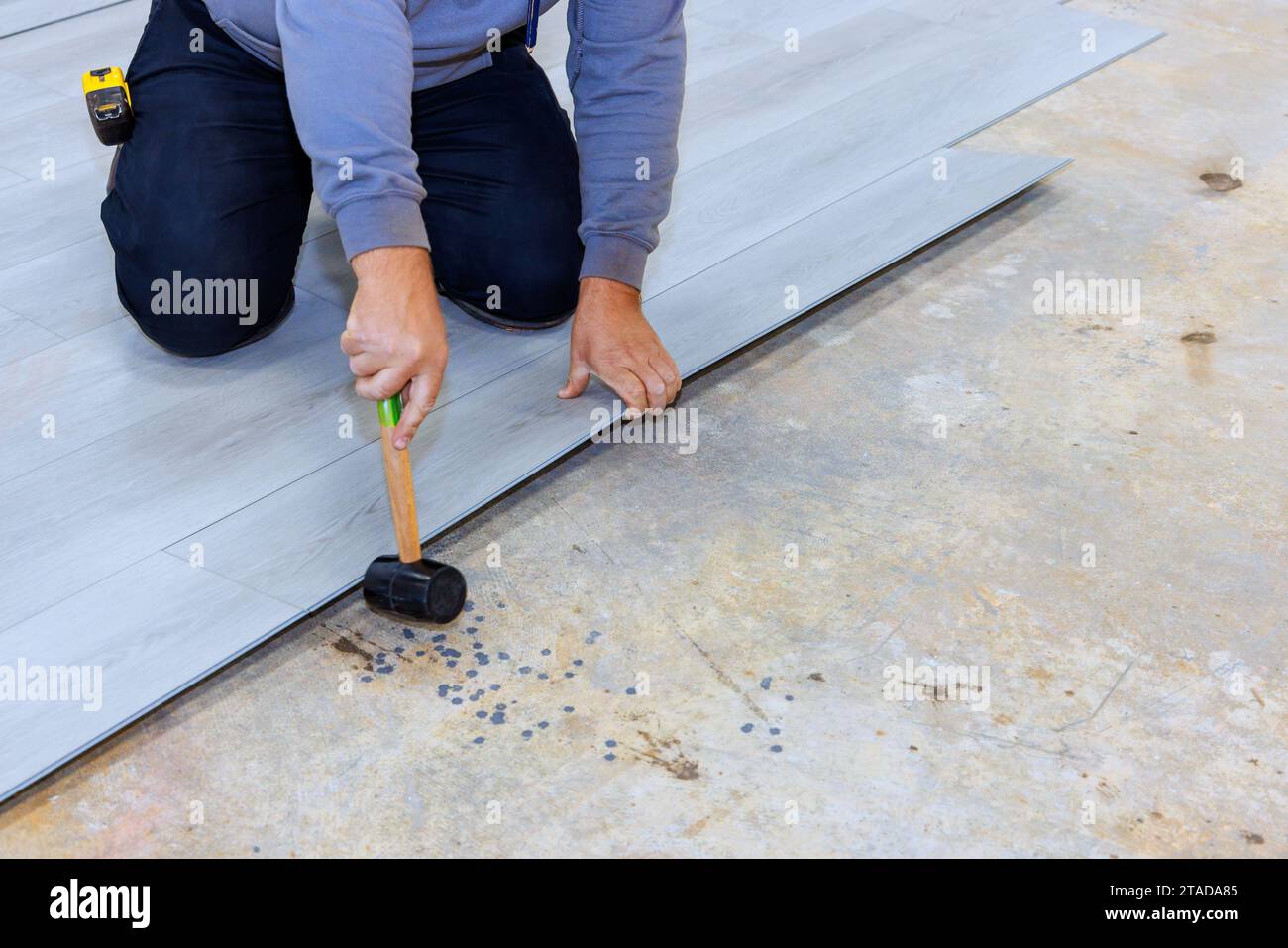 Installing vinyl laminate flooring in new home by construction worker Stock Photo