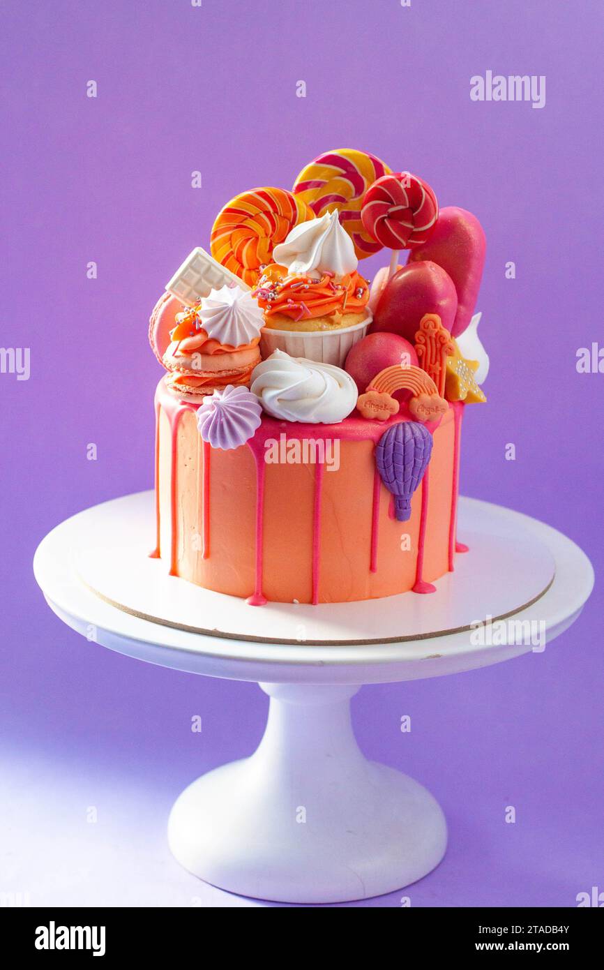 Tasty orange cake with sweets on plain purple background Stock Photo