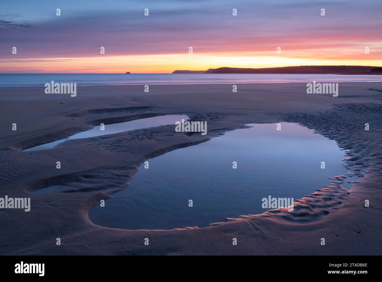 Colourful sunrise over tidal pools on a deserted Harlyn Beach, Cornwall, England. Spring (April) 2022. Stock Photo