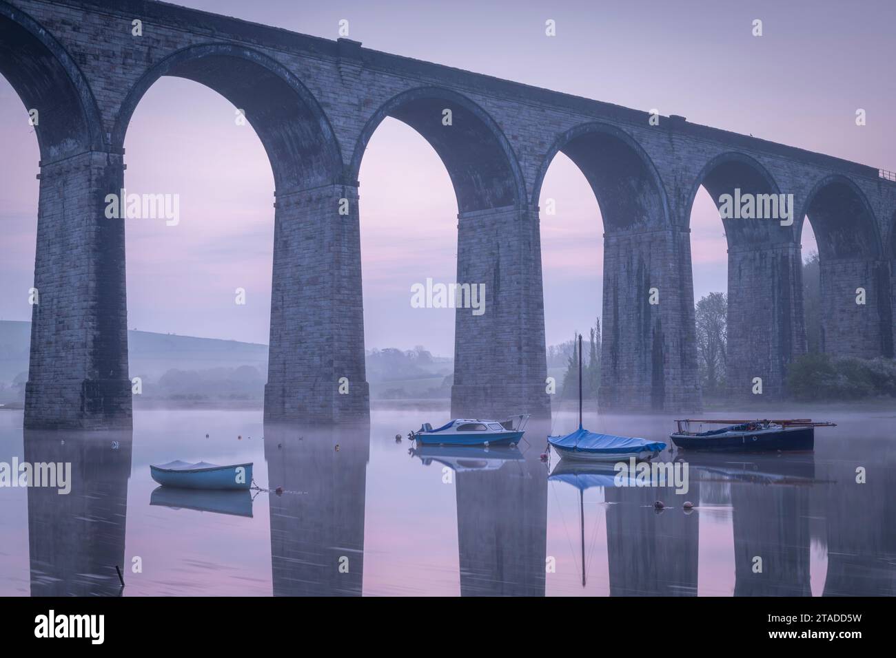 Boats beneath St Germans Victorian viaduct at dawn, St Germans in Cornwall, England.  Spring (April) 2022. Stock Photo