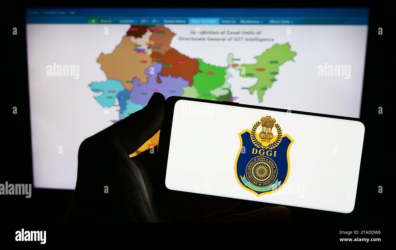 Person holding smartphone with logo of Indian Directorate General of GST Intelligence (DGGI) in front of website. Focus on phone display. Stock Photo