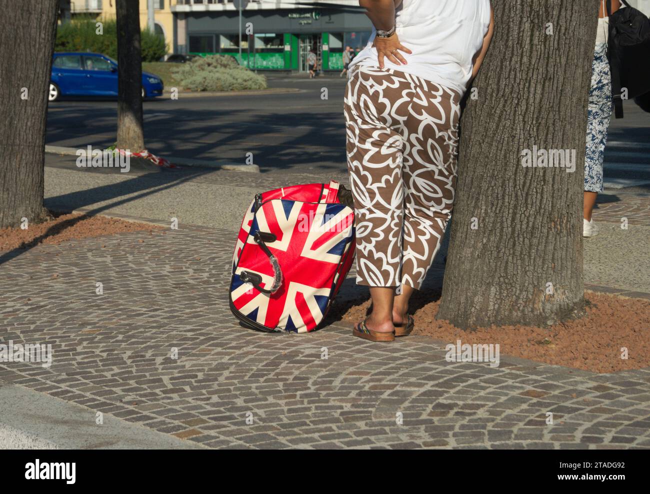 tourist woman with union jack flag trolley case bag leaning against a