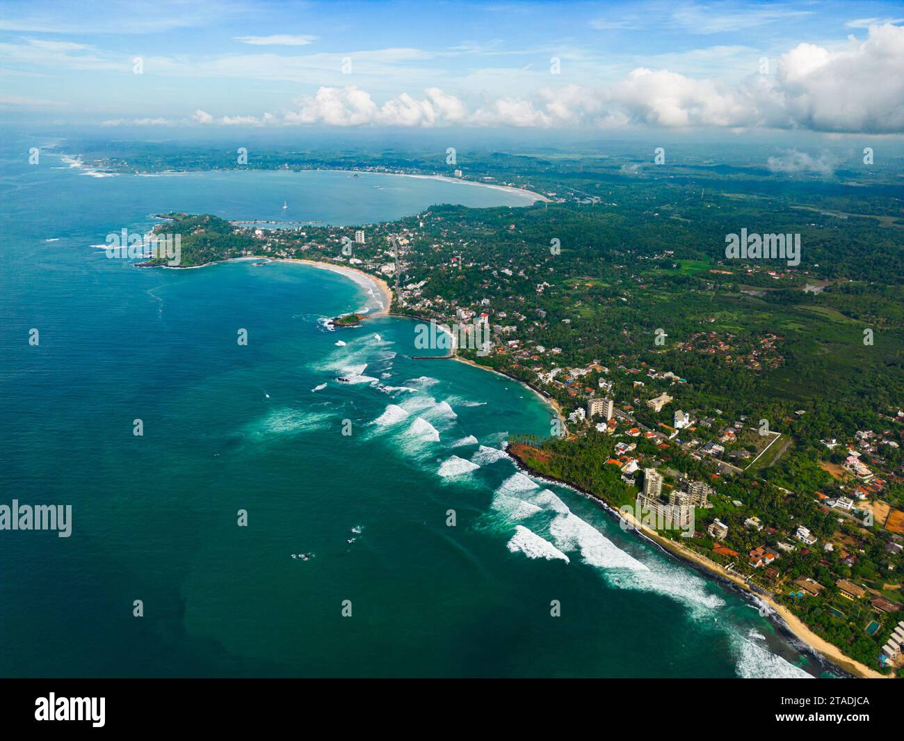 Aerial view with panoramic coastline with sparkling turquoise waters against a lush green landscape, showcasing scenic coastal living and the junction Stock Photo