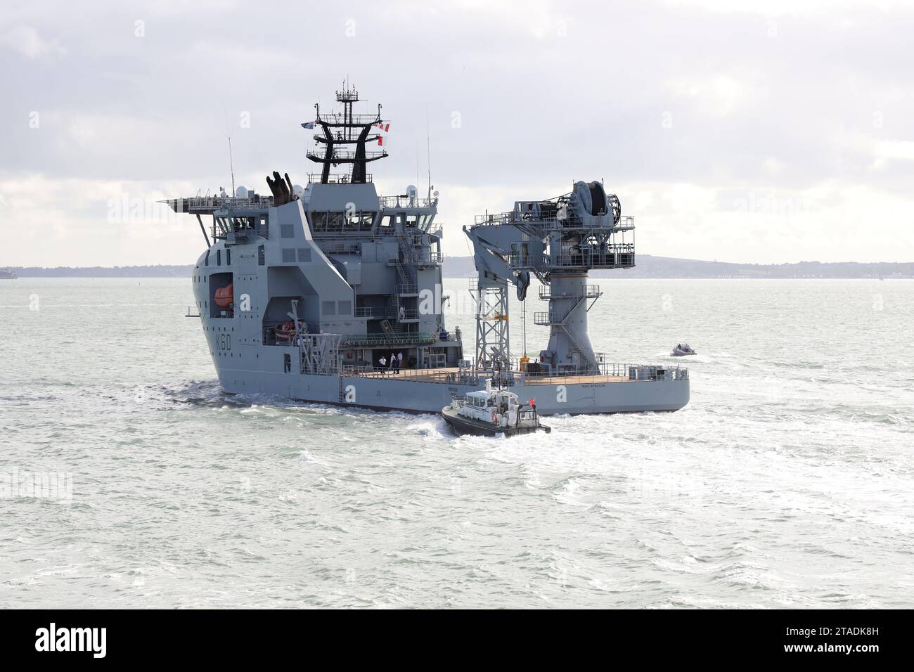 The Admiralty pilot’s launch stays close to the stern of the Royal Fleet Auxiliary’s latest ship RFA PROTEUS as the vessel heads into The Solent Stock Photo