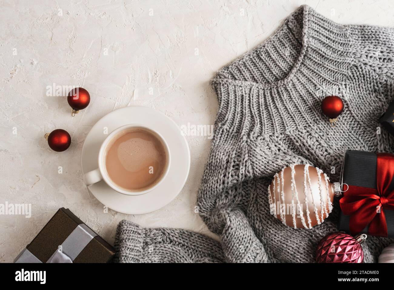 A cup of coffee and Christmas gifts on grey sweater on white background. Top view, flat lay. Stock Photo