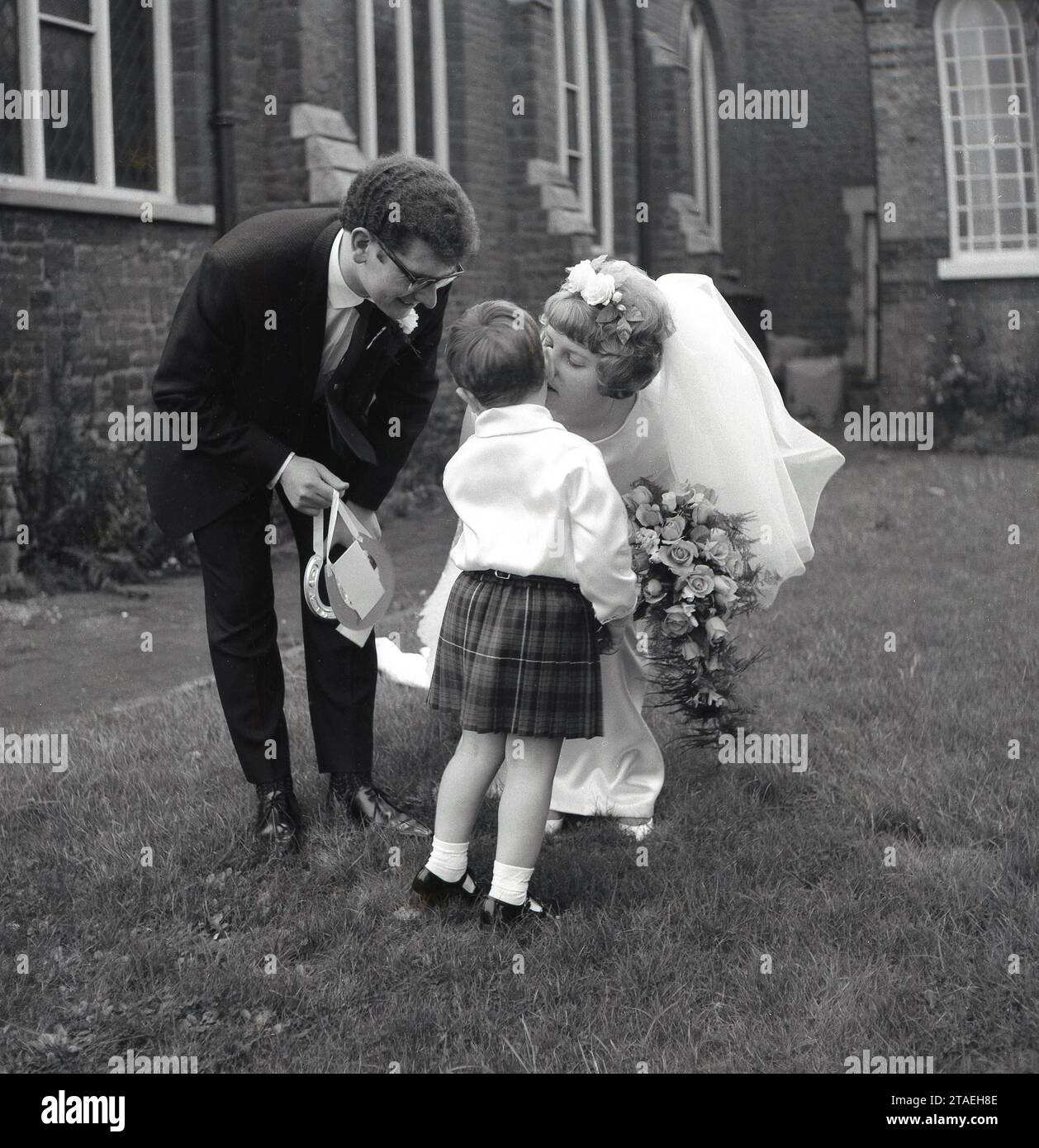 1960s, historical, wedding, in the grounds of a church, a kiss on the