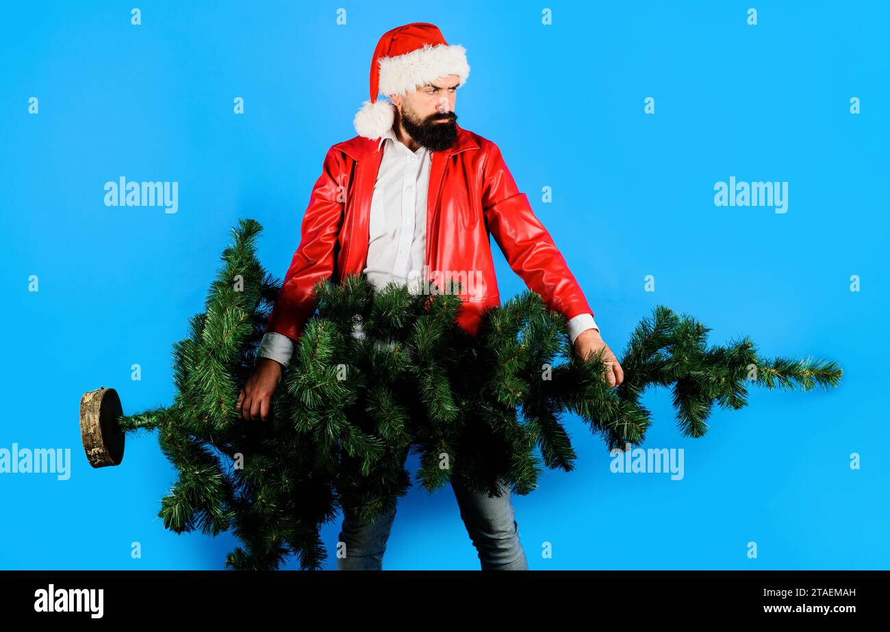 Merry Christmas and Happy New year. Winter holidays celebration. Delivery man in Santa hat and red coat with Christmas tree. Christmas Santa man with Stock Photo