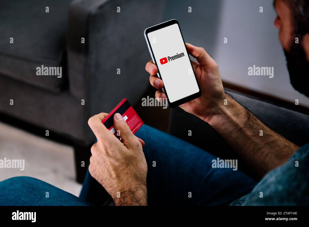 Youtube premium app on smartphone screen. Man making payment for premium application with credit card. Stock Photo
