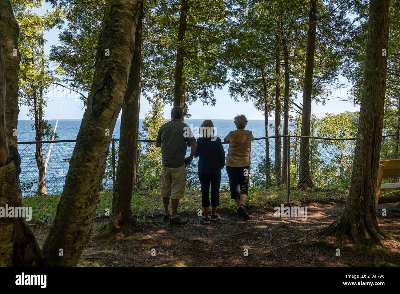 DOOR CO, WI - 15 AUG 2023: Three seniors citizens viewing a lake scene overlook in wooded area of a Wisconsin State Park. Stock Photo