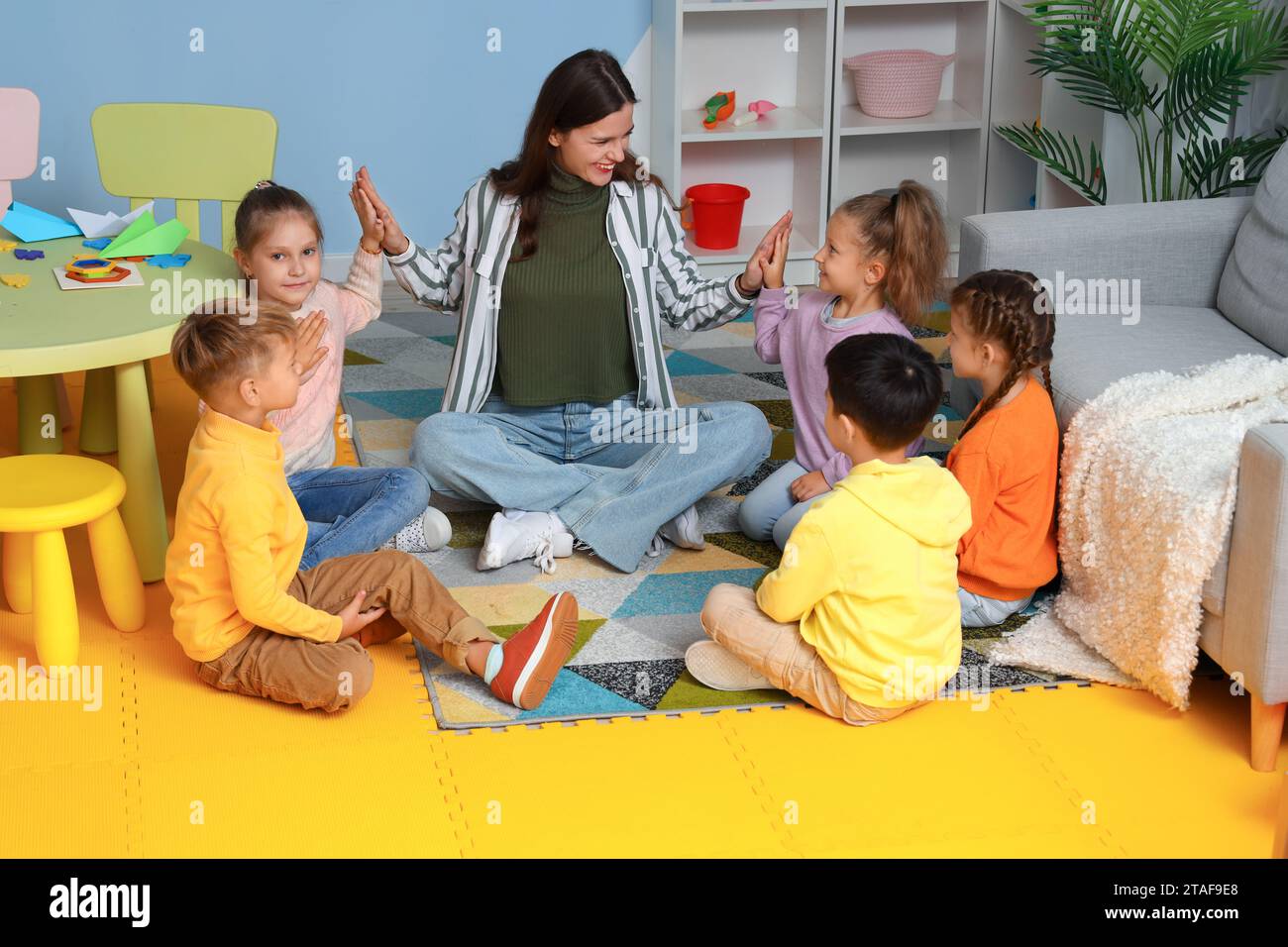 Little children with nursery teacher holding hands in kindergarten Stock Photo