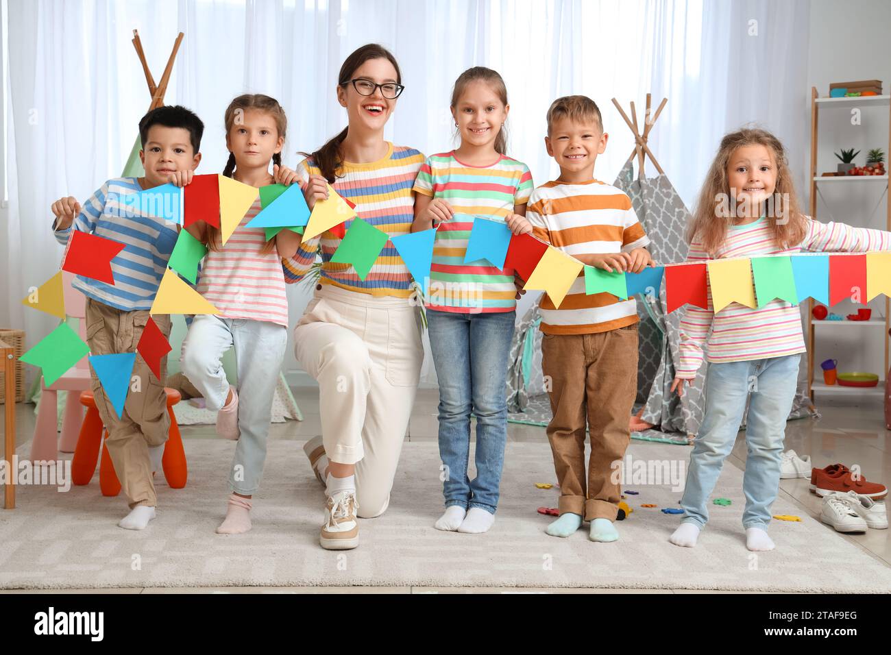 Little children with nursery teacher and paper flags in kindergarten Stock Photo
