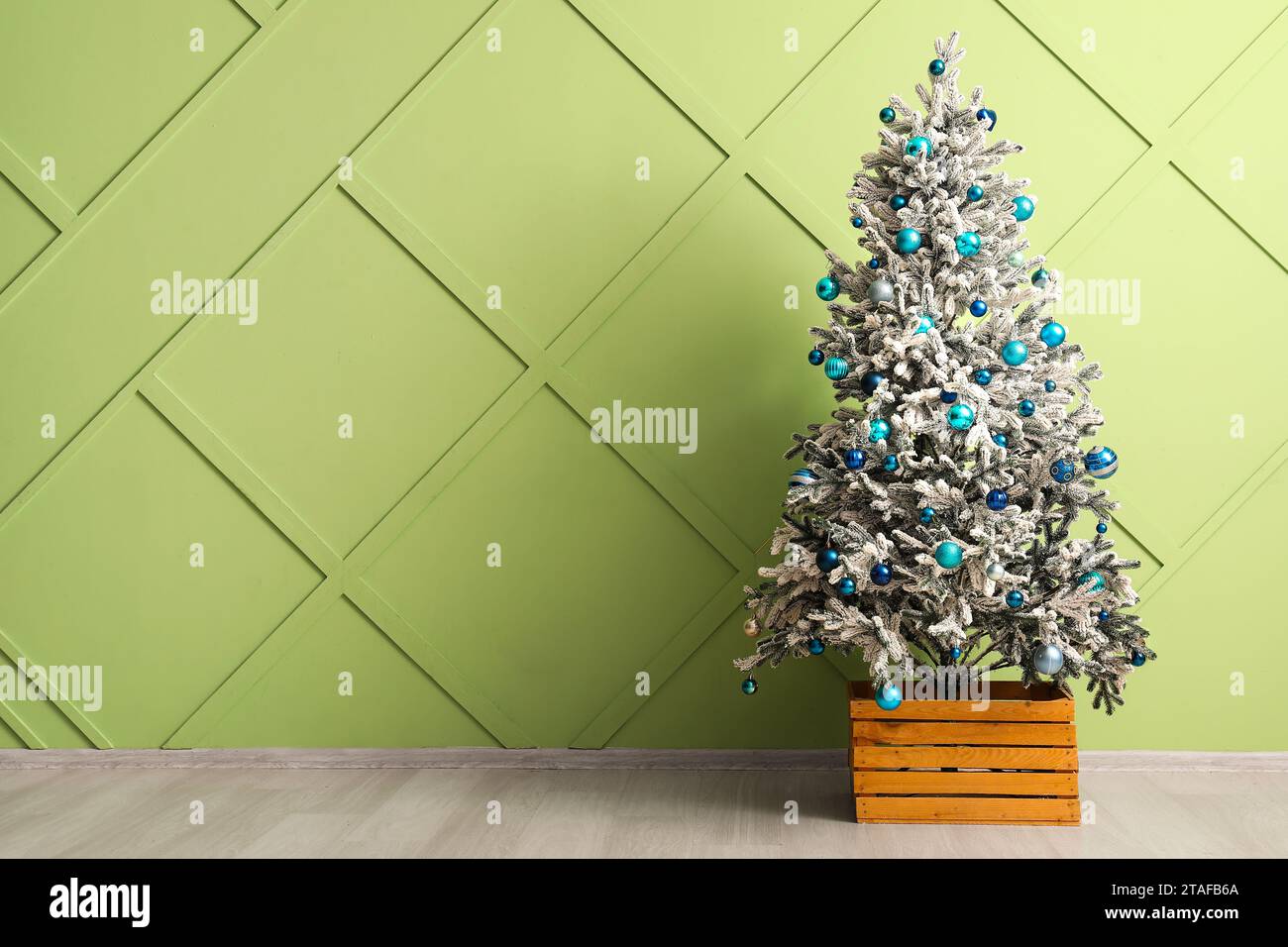 Beautiful Christmas tree decorated with different balls near green wall ...