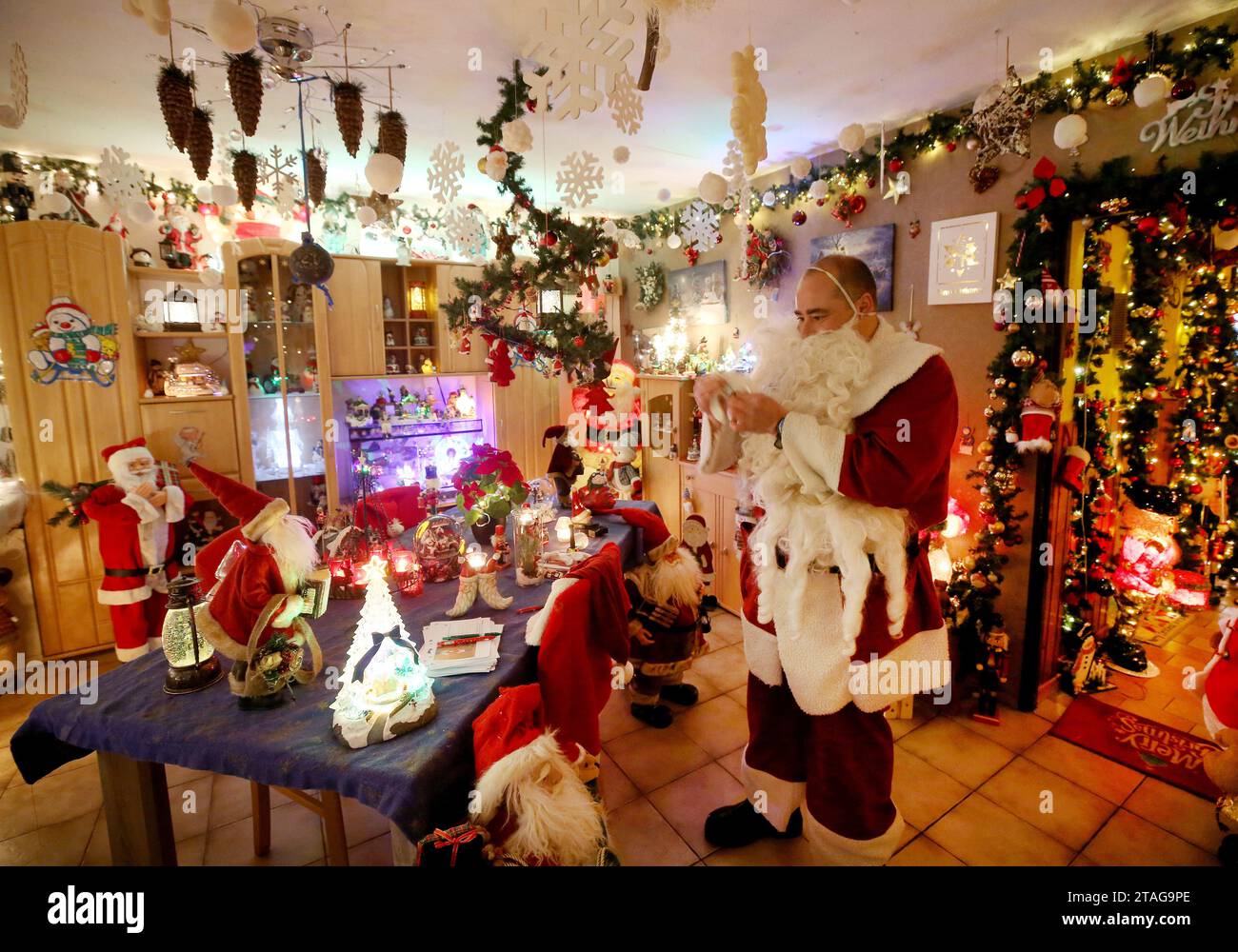 Oberhausen, Germany. 29th Nov, 2023. Dirk van Acken, a geriatric nurse and Christmas fanatic, dresses up as Santa Claus in his decorated house. Around 70,000 lights are lit up around the house and inside there is a veritable frenzy of decorations: nutcrackers, reindeer, mini Christmas houses, countless figures and Christmas knick-knacks. Credit: Roland Weihrauch/dpa/Alamy Live News Stock Photo