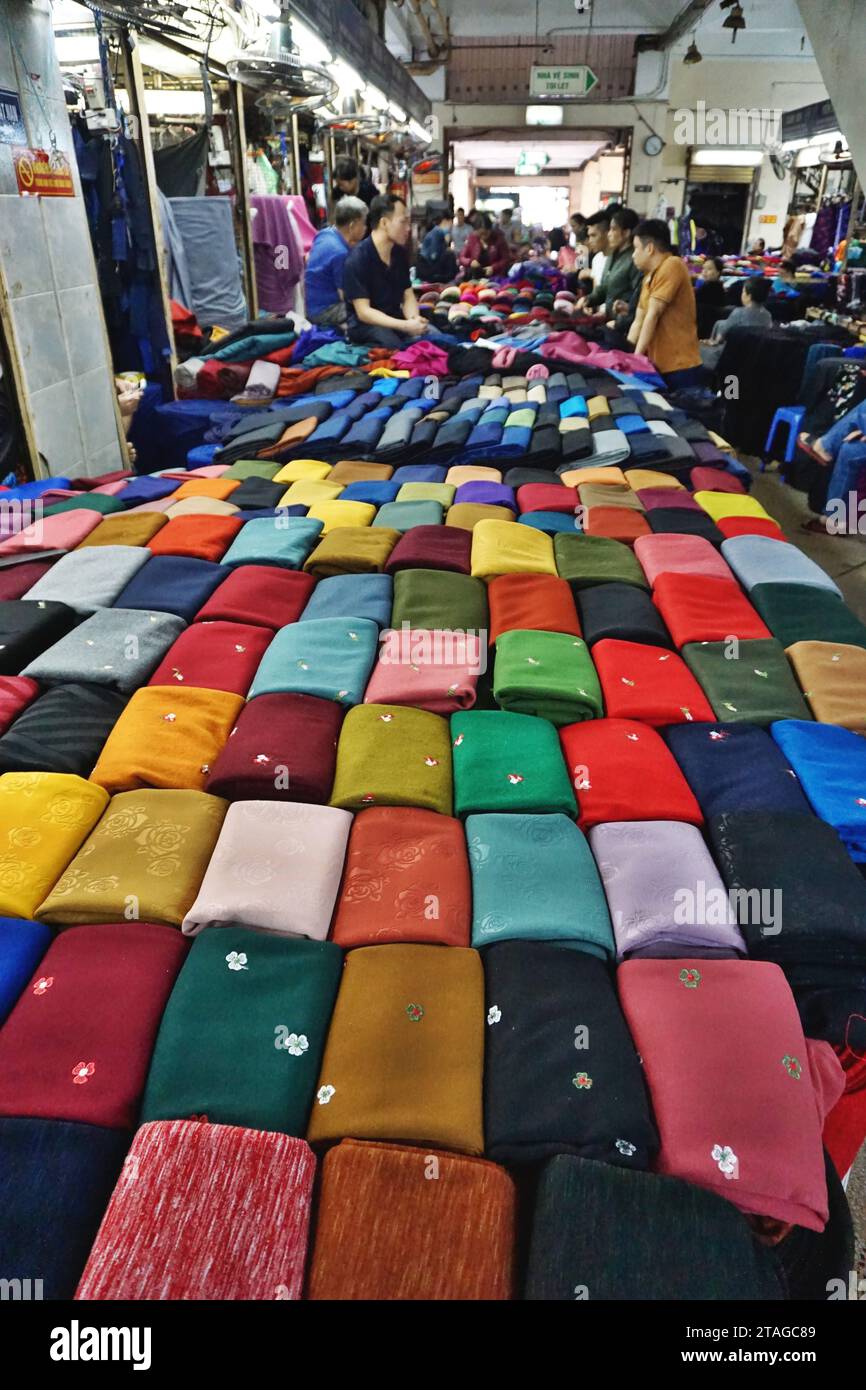 Folded bolts of colorful fabric for sale at a wholesale cloth market in Hanoi, Vietnam. Many of the textiles offered are finely woven silk brocades Stock Photo
