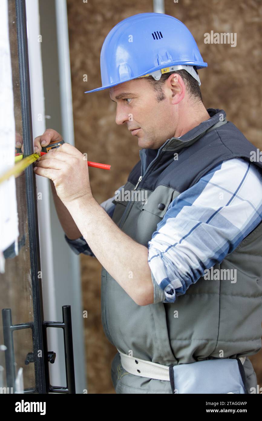 male builder is measuring a window Stock Photo