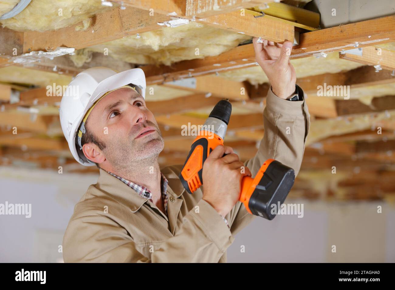 man drilling a hole in white ceiling Stock Photo